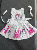 Children's dress with unicorn and rainbow designs on a dark surface