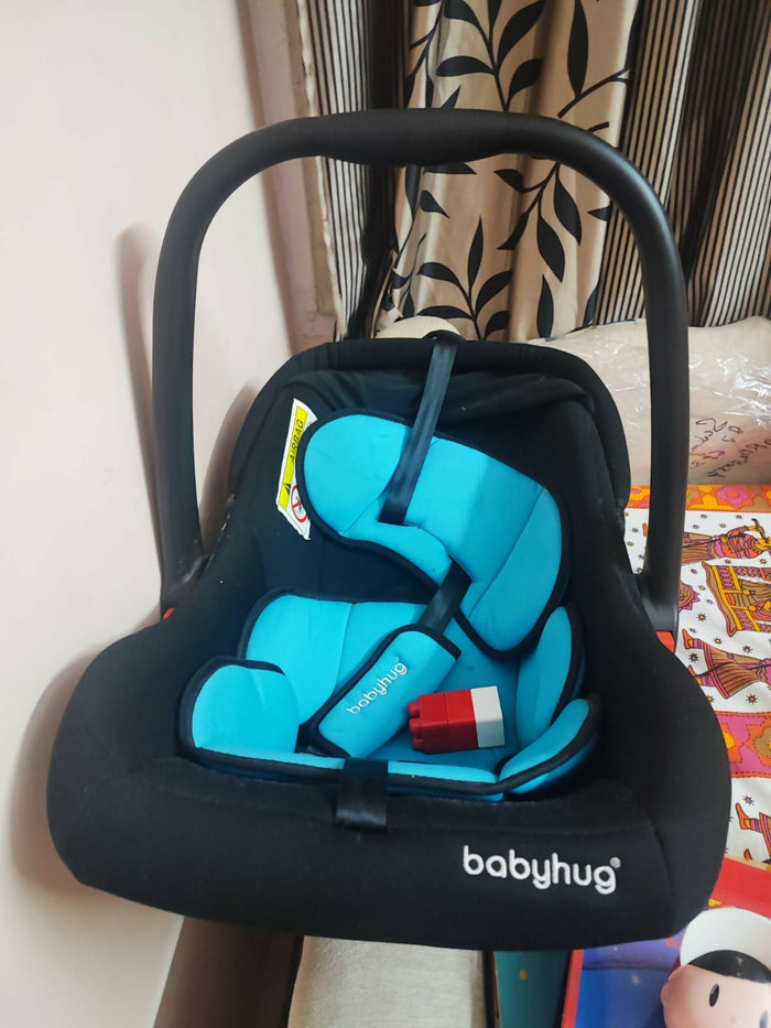 BABYHUG Amber Car Seat Cum Rocker in Almost New condition, featuring comfortable padded seating, safety harness, ergonomic carry handle, protective canopy, and versatile rocking function for convenient infant travel and supervised relaxation.