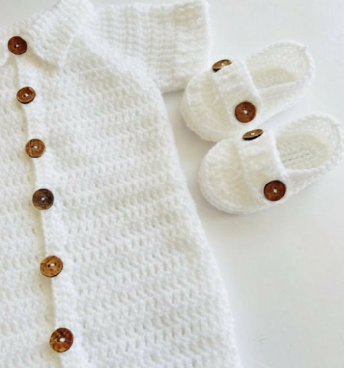 White baby outfit with buttons and white baby shoes