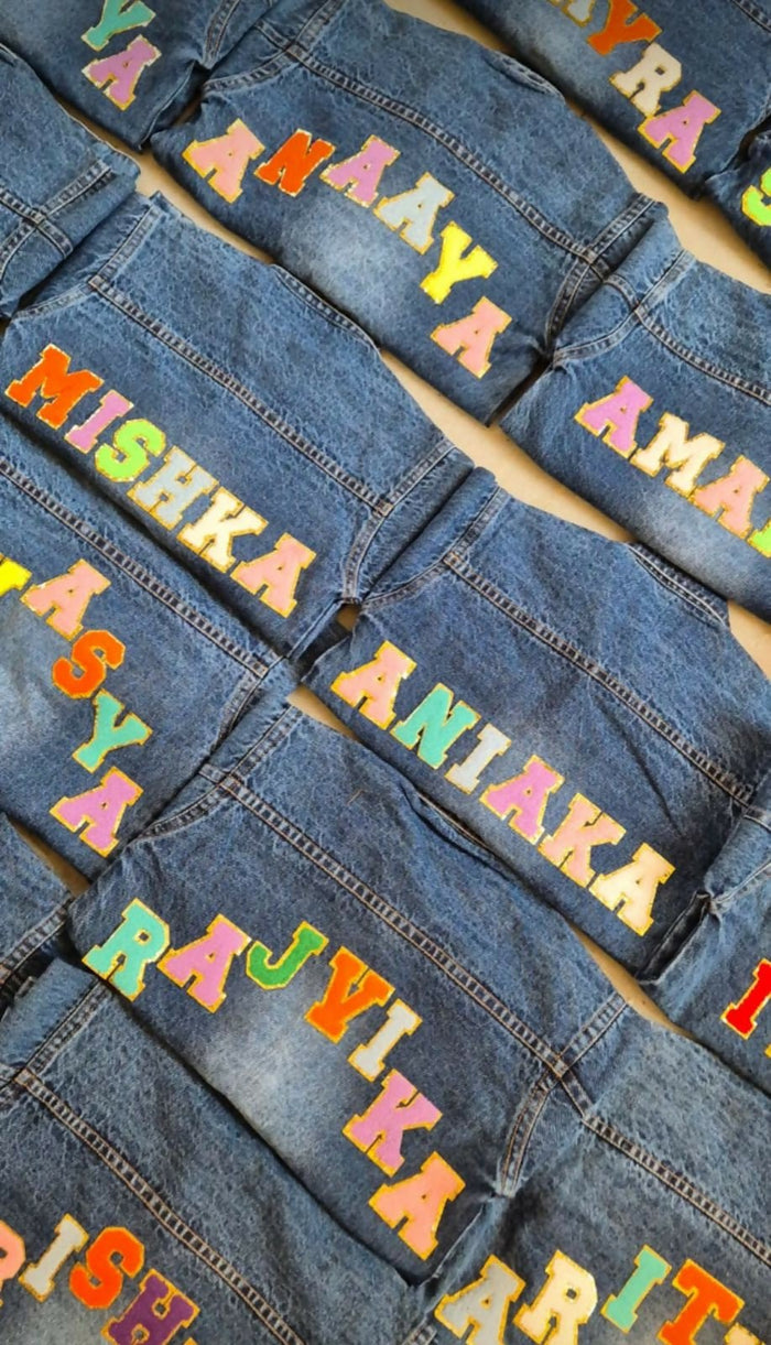Denim jackets with colorful text labels on a flat surface