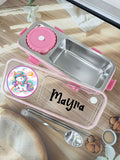 Stainless steel lunch box with pink accents and personalized name on a wooden surface.
