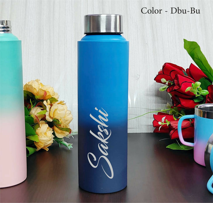 Blue water bottle with 'Sakshi' branding on a wooden surface with flowers in the background