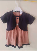 Children's outfit with black top and pink shorts on a hanger against a white background