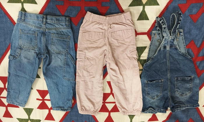 Three pairs of children's pants on a patterned rug