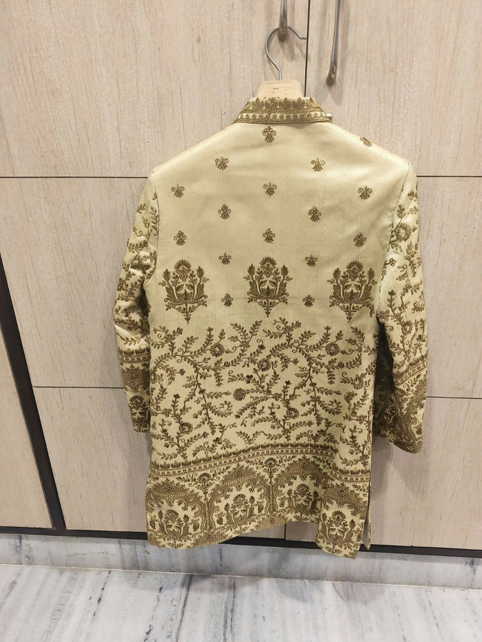 Embroidered traditional jacket on a hanger against a light wooden panel background