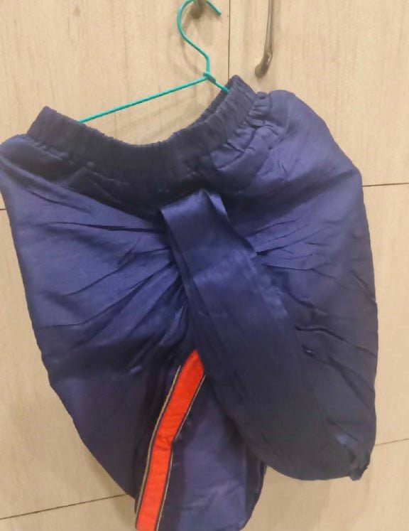 Blue jacket with a red zipper on a hanger against a tiled wall.