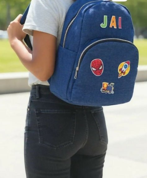 Person wearing a blue backpack with colorful patches and 'JAI' branding.