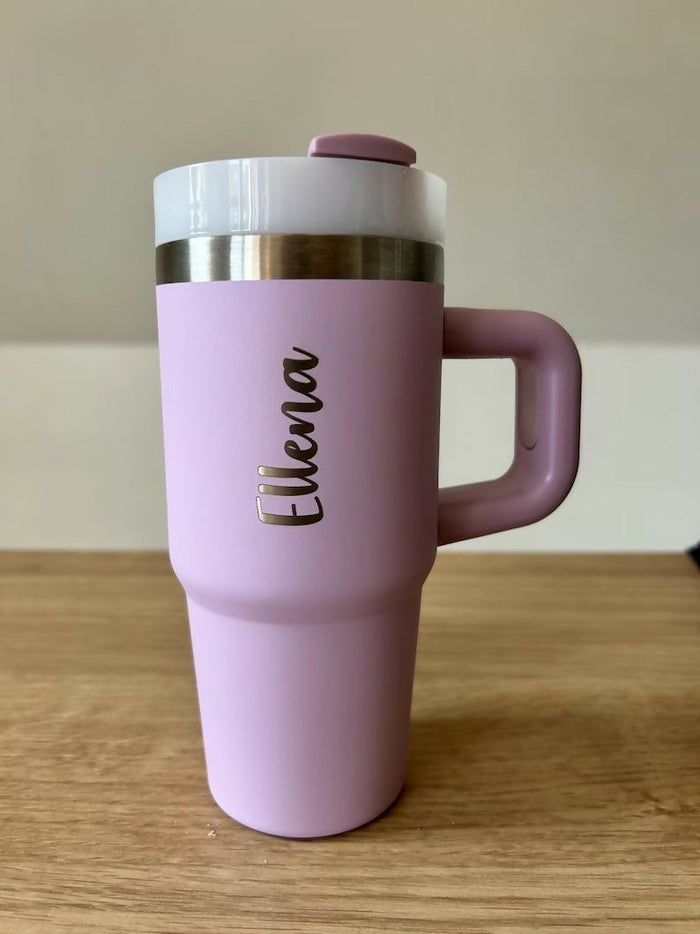 Pink travel mug with a handle on a wooden surface