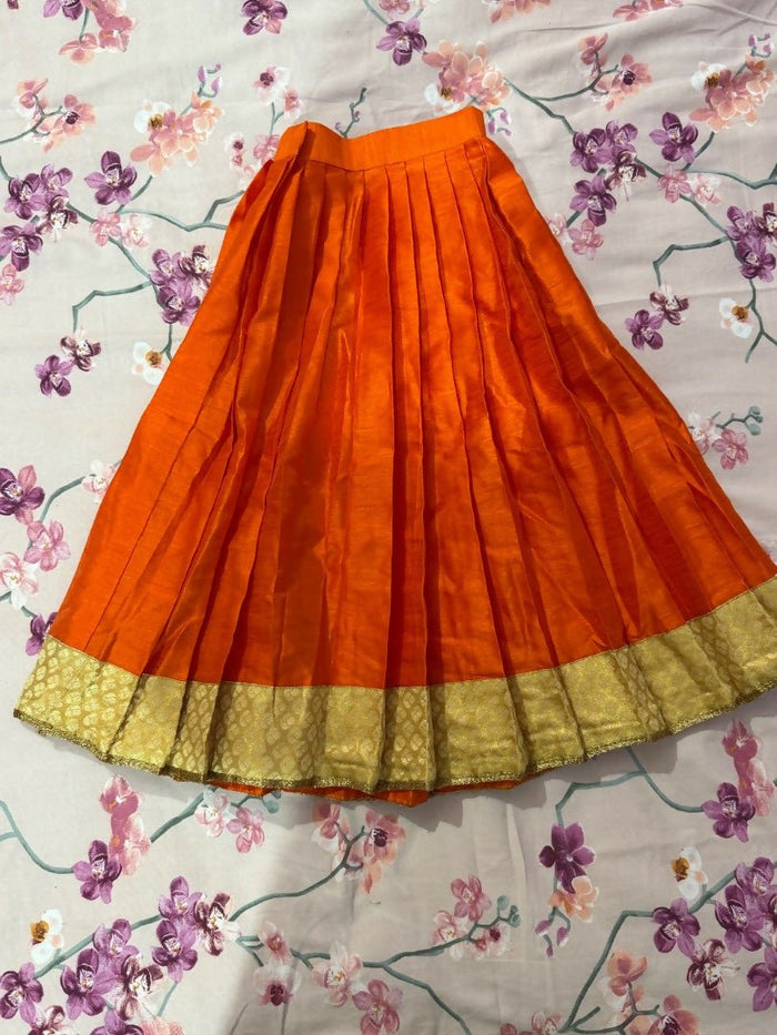 Orange skirt with gold hem on a floral-patterned fabric background